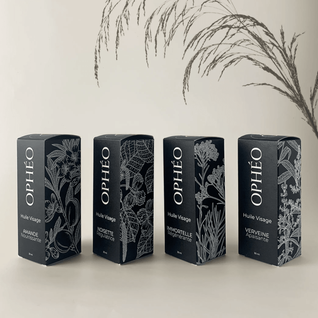 Les quatre huiles visage OPHÉO dans un packaging élégant noir et blanc avec illustrations botaniques.