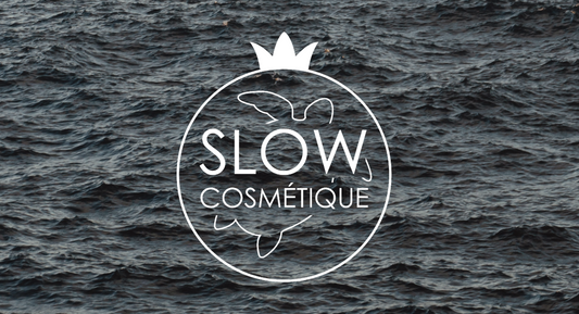 Logo du label Slow Cosmétique. En arrière plan, la mer d'un bleu marine foncé.