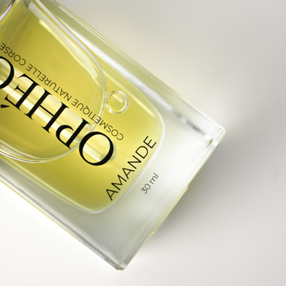 Zoom sur un flacon d'Huile Visage Amande Nourrissante de la marque OPHÉO. On y voit en détail le flacon en verre et l'huile végétale d'amande douce de couleur dorée.