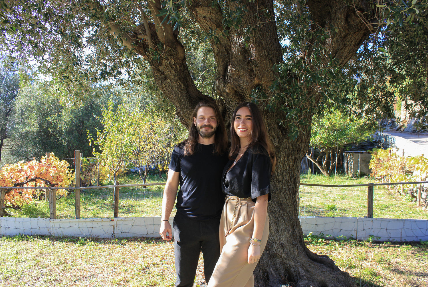 Photo des fondateurs d'OPHÉO se tenant sous un olivier dans le jardin d'un village corse.
